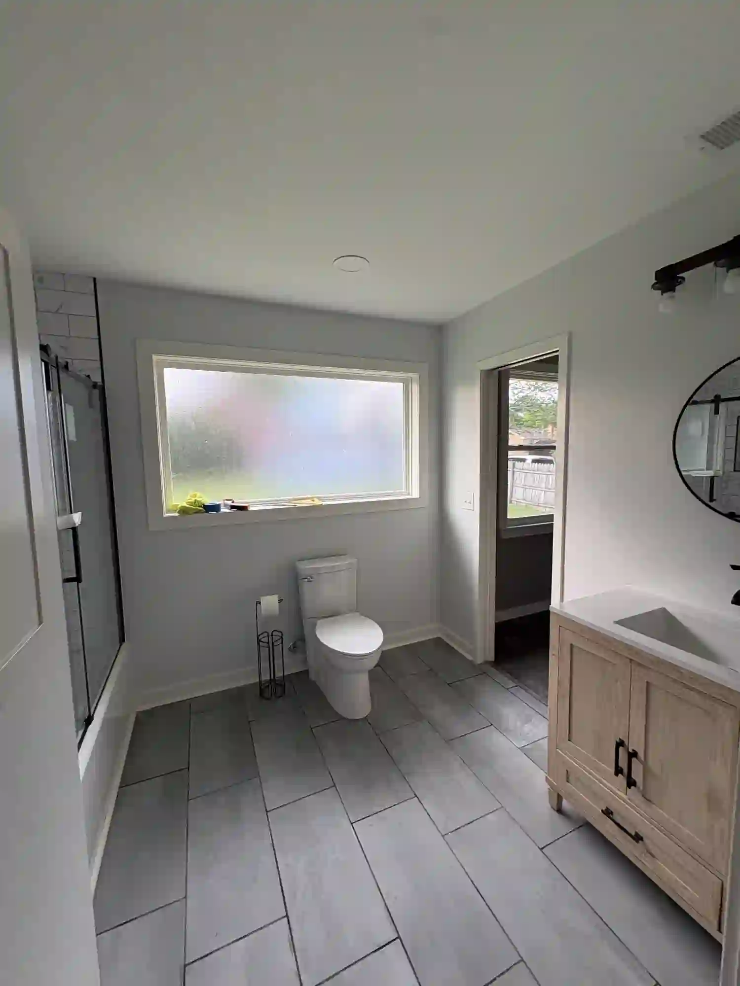 Finished bathroom with light oak vanity and gray tile floor