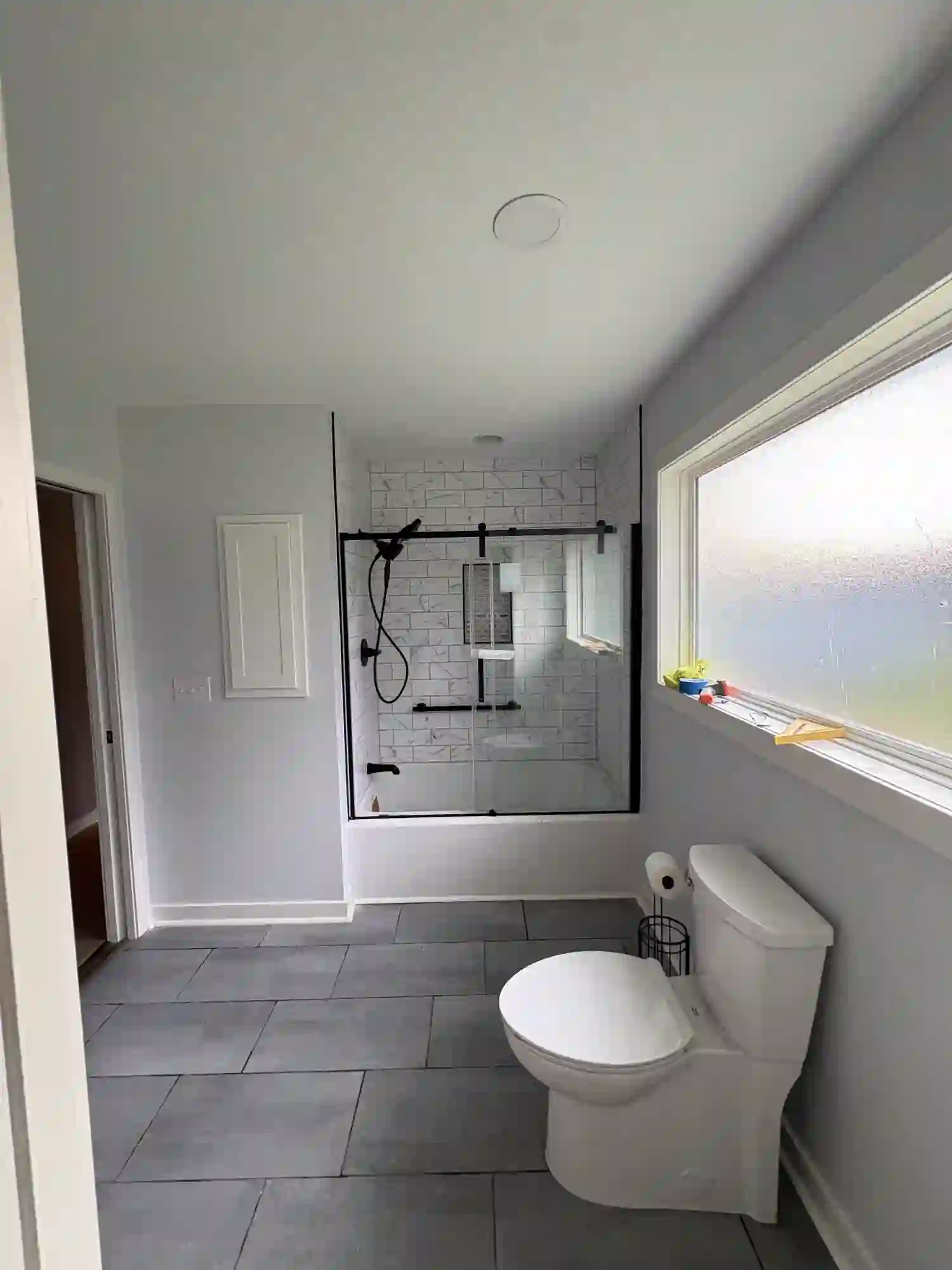 New subway-tile tub surround with black-framed glass and matte black fixtures