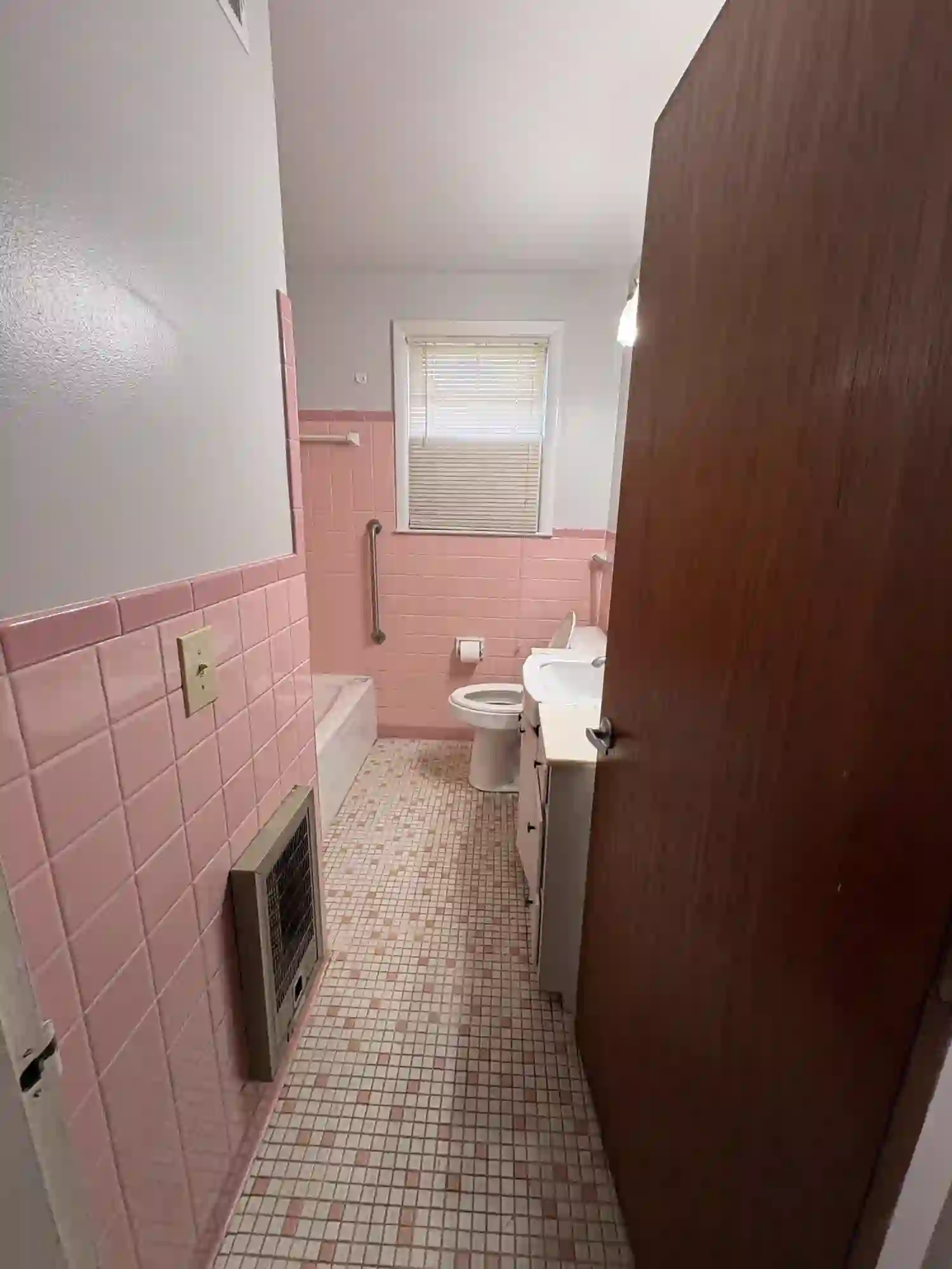 Original pink-tile bathroom with dark wood door