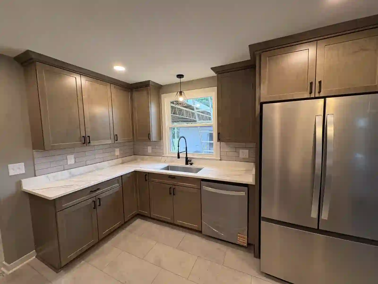Wide view of finished kitchen with stainless refrigerator and gas cooktop