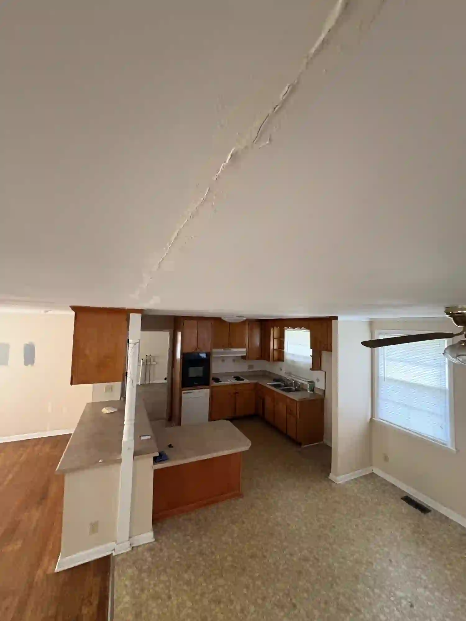 Original kitchen with brown cabinets and cracked popcorn ceiling
